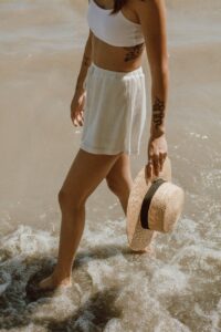 Chic Style Collective | 10 Stunning Summer Accessories from Amazon summer accessories woman in white and blue stripe skirt and brown sun hat standing on water
